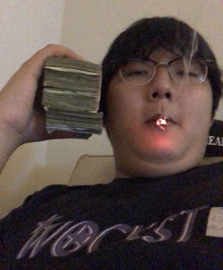 Fat Asian Guy with money next to his face, smoking a cig
